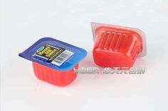 two plastic containers sitting next to each other on a white surface, one has a blue lid and the other is red