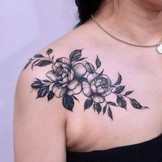 a woman's shoulder with flowers and leaves on it