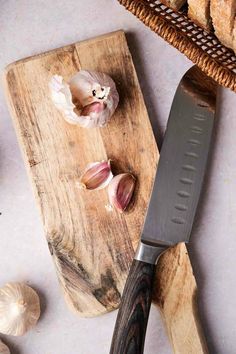 garlic on cutting board next to bread and knife