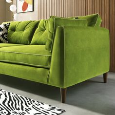 a green couch sitting on top of a white rug