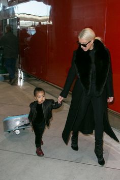 a woman and child are walking through an airport