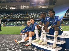 three soccer players sitting on the sidelines in front of an empty stadium with confetti all around them