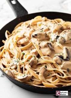 a skillet filled with pasta covered in mushrooms and sauce on top of a marble counter