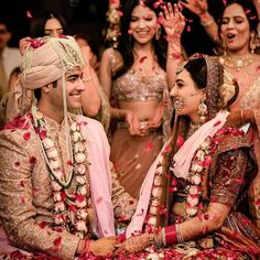 the bride and grooms are surrounded by petals as they sit on the floor in front of their guests