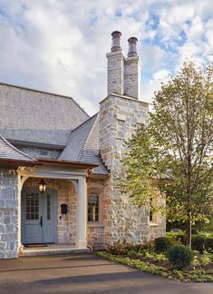 a stone house with two chimneys on the roof and a blue front door is shown