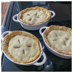 three pies sitting on top of a stove next to each other in pans