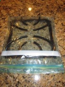 a glass stove top sitting on top of a counter next to a plastic container with scissors in it