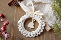 a crocheted christmas ornament hanging from a tree on a wooden table