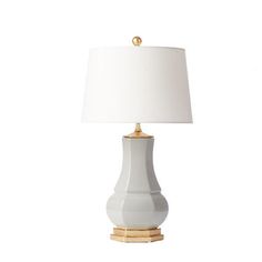 a white table lamp with a gold base and a white linen shade on the top