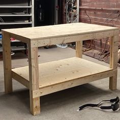 a wooden table sitting in front of a brick wall next to a pair of pliers