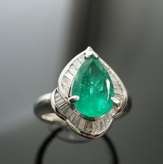 "Colombian Pear Shaped 1.86ct Emerald Ring D:0.62ct Emeralds are mined in many countries; however, Colombian emeralds are often the most prized as they have a very pure colour and are reputed as being one of the most natural gemstones. It is also regarded as May Birthstone in western astrology. A lovely platinum made ring featuring a 1.86 carat pear-shape Colombian emerald. It has a bright gem green color with excellent brilliance and life. It Is accented by 0.62 carats of baguette diamonds set Green Wedding Rings, Western Astrology, Promise Rings Vintage, Smaragd Ring, Emerald Ring Gold, Gold Promise Rings, Cluster Engagement Ring, Baguette Diamonds, Promise Rings For Her