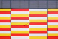 the side of a building painted in red, yellow and white colors with vertical stripes