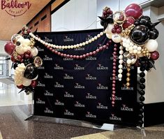 balloons and streamers are attached to a backdrop at an airport lobby for a corporate event