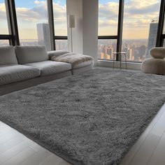 a living room with large windows and a gray rug in front of the couches