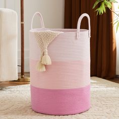 a pink and white striped basket with a tassel hanging from it's side