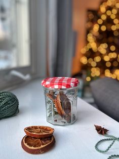 a glass jar filled with dried fruit sitting on top of a table next to a christmas tree