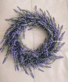 a wreath made out of purple flowers sitting on top of a white couch next to a pillow