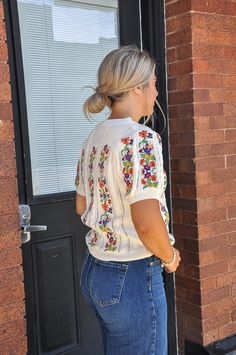 a woman standing in front of a black door with her back turned to the camera