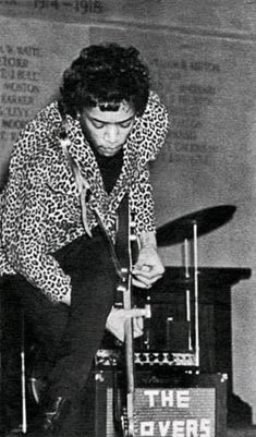 an old black and white photo of a man playing the guitar in front of a microphone