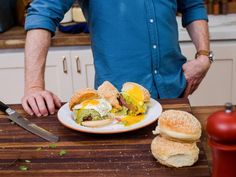 a man standing in front of a plate with sandwiches on it