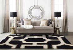 a black and white rug in front of a couch with two lamps on either side