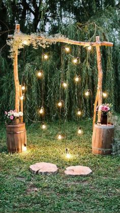 an outdoor ceremony with wooden barrels and string lights on the grass, surrounded by greenery