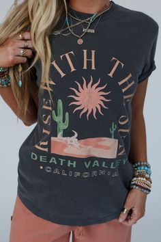 Embrace the dawn of a new day with our Rise With The Sun Graphic Tee, this cool graphic is perfect for all your boho ensembles and will have you wanting to wear it from sunrise to sunset! Comfortable, soft, mineral - washed tee shirt fabric Relaxed tee shirt silhouette Classic ribbed crew neckline and loose short sleeves So cute "Rise with the Sun" desert center graphic Pair with: Dora Low Back Seamless Bralette, High Hopes Slouchy Denim Overalls and Sacred Stone Beaded Bracelet Set. *Due to lig Boho Essentials, Sun Graphic, Shirt Silhouette, Bralette Outfit, The Dawn, Loose Shorts, Sweater Sale, Shirt Fabric, New Tops