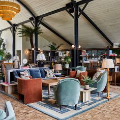 a living room filled with lots of furniture next to a wooden floor covered in potted plants