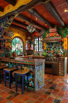 the kitchen has colorful tiles on the walls and floor, as well as an island with stools