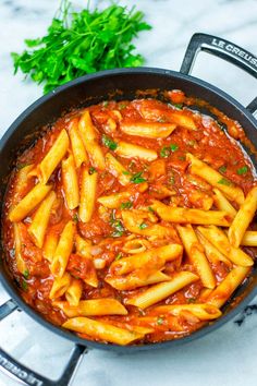 pasta with tomato sauce and parsley in a skillet on a marble counter top