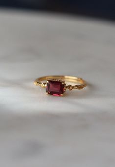 a gold ring with a red stone on it