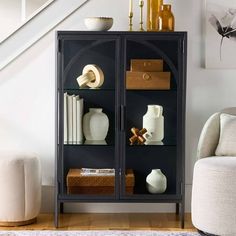 a black bookcase with books and vases on it in front of a stair case