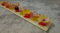 there are many small pieces of gummy bears on a white plate with red, yellow, and blue candies