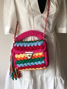 a pink, green, yellow and red purse sitting on top of a white dress