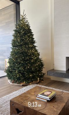 a living room with a christmas tree in the corner and a fire place on the floor