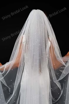 the back of a bride's veil with white beads on it and her dress