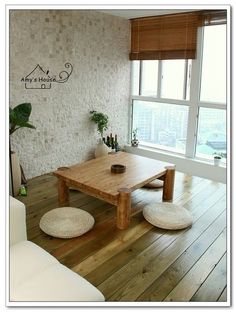 a living room with wood flooring and white furniture in front of a large window