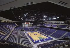 an empty basketball court with blue seats and lights