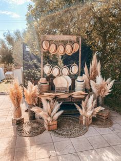 an outdoor table with plates and vases on it