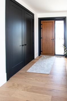 an empty room with wooden floors and black doors on either side of the entryway