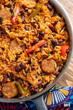 a large pot filled with rice, beans and sausage on top of a wooden table