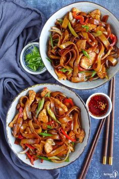 two bowls filled with stir fry chicken and veggies next to chopsticks