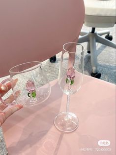 two wine glasses sitting on top of a pink table