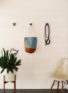 two chairs and a potted plant in a room with white paneling on the wall