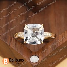 a white topazte ring sitting on top of a wooden box with a diamond in it