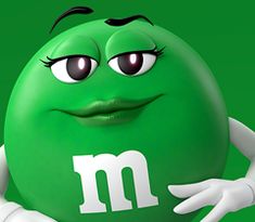 a green m & m's egg with eyes and hands on its chest, holding it