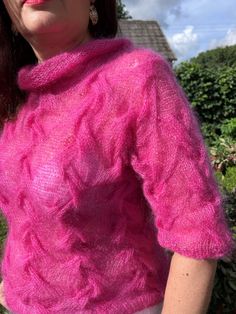 a woman wearing a pink sweater and white pants