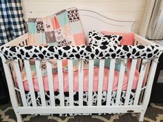 a white crib with pink and black pillows on it