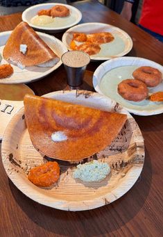 several plates with donuts on them sitting on a wooden table next to each other