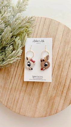 a pair of earrings on top of a wooden table next to a potted plant